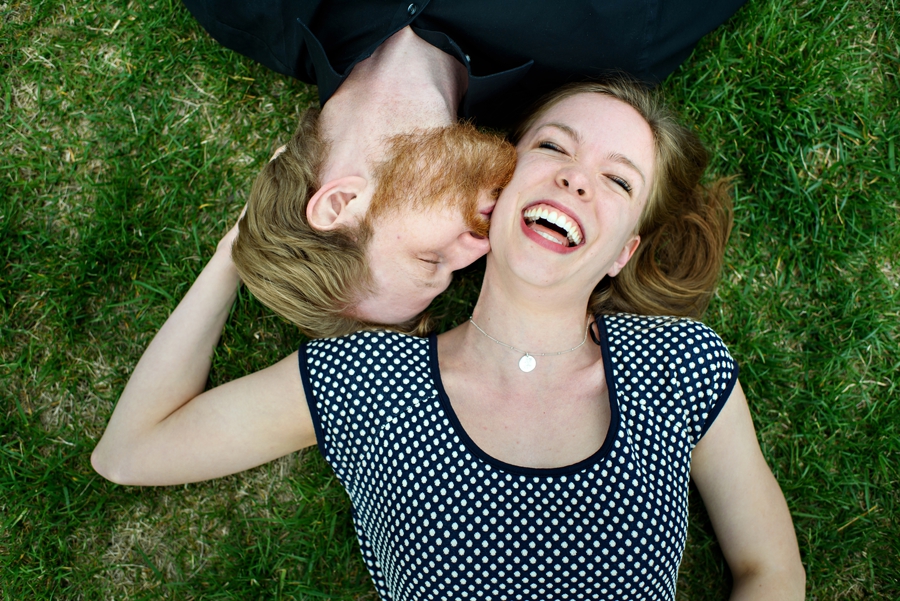 An engaged couple lay in the grass at cira green during their fun philadelphia engagement session.